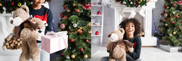 Colagem de menina americana africana alegre segurando ursinho de pelúcia e caixa de presente, enquanto sentado no chão perto de lareira e árvore de natal no fundo borrado, banner — Fotografia de Stock