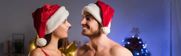 Couple joyeux chapeaux santa se regardant, bannière — Photo de stock