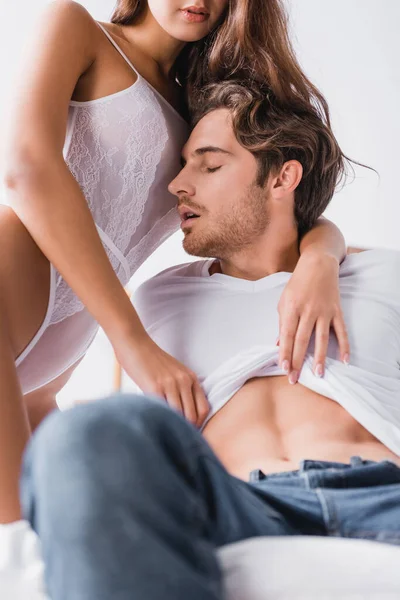 Sexy man kissing girlfriend in white bodysuit at home — Stock Photo