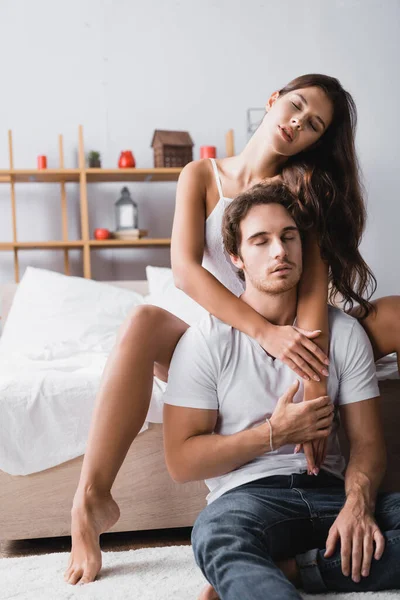 Sexy woman hugging boyfriend with closed eyes in bedroom — Stock Photo