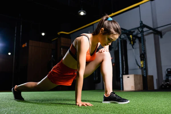 Deportista atlética haciendo adelante se lanza ejercicio mientras se calienta en el gimnasio - foto de stock