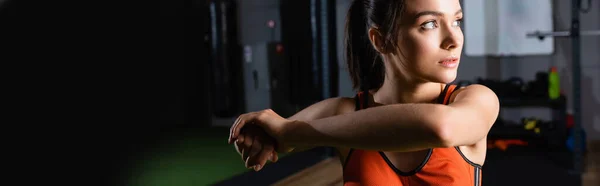 Femme de sport en soutien-gorge de sport regardant loin tout en réchauffant les bras, bannière — Photo de stock