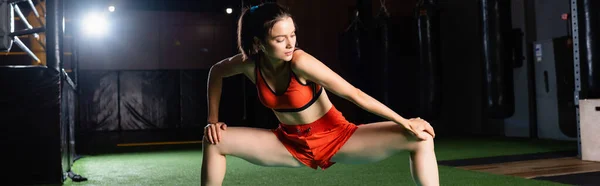 Deportista atlética que estira las piernas mientras entrena en el gimnasio, bandera - foto de stock