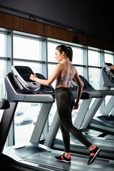 Athletic sportswoman in leggings exercising on treadmill in gym — Stock Photo