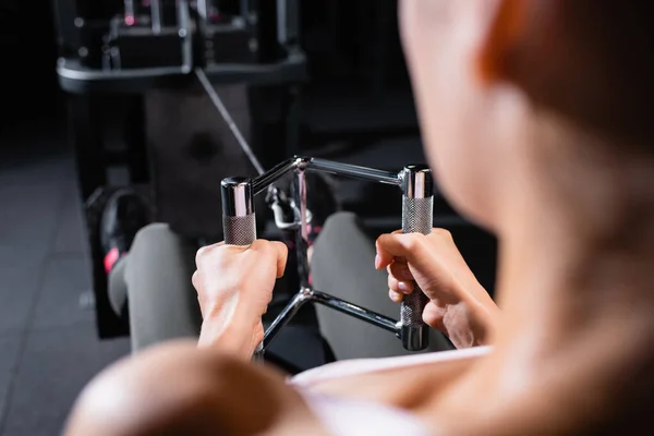 Cropped view of sportswoman training on rowing machine on blurred foreground — Stock Photo