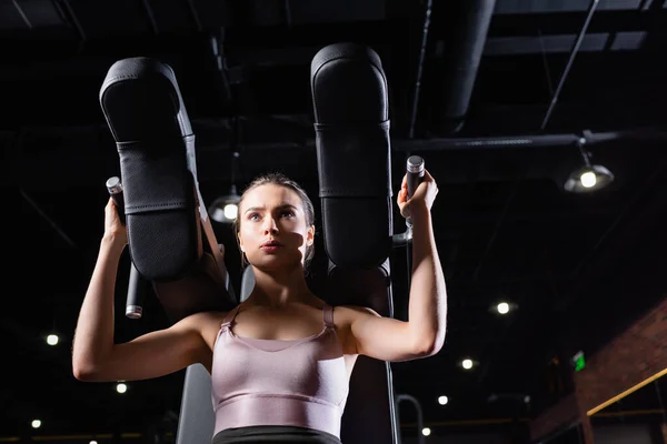 Low angle view of athletic sportswoman training on arms extension machine — Stock Photo