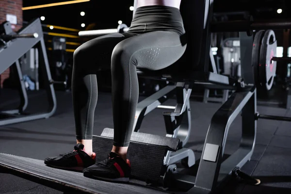 Cropped view of sportswoman in leggings and sneakers working out on exercising machine — Stock Photo