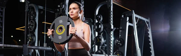 Athletic sportswoman working out with weight disk in sports center, banner — Stock Photo