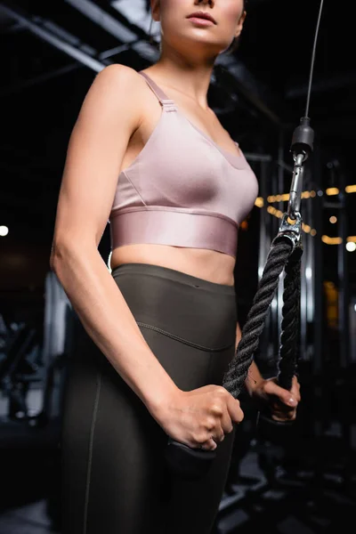 Vista parcial de la mujer deportiva en sujetador deportivo y legging ejercicio en la máquina de extensión de tríceps — Stock Photo