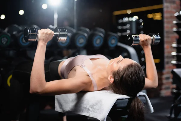 Entraînement de femme sportive avec haltères en position couchée dans le centre sportif — Photo de stock