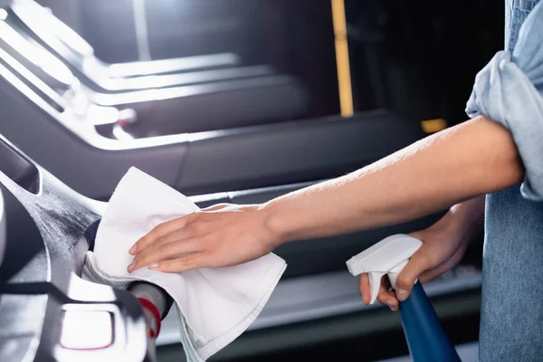 Vue recadrée de charwoman tenant le vaporisateur tout en essuyant le tapis roulant dans le centre sportif sur fond flou — Photo de stock