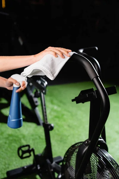Cropped view of charwoman wiping exercising machine in sports center — Stock Photo