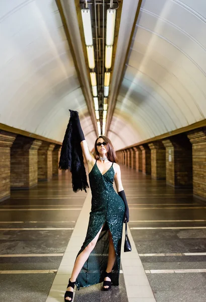 Mulher na moda em vestido lurex preto longo em óculos de sol posando na estação de metro — Fotografia de Stock