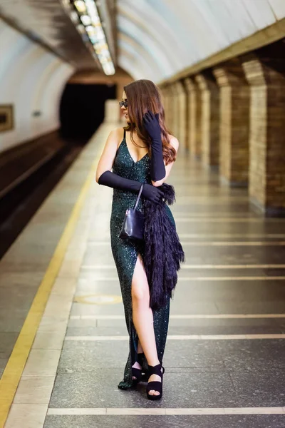 Fashionable woman in long black dress standing on subway platform - foto de stock