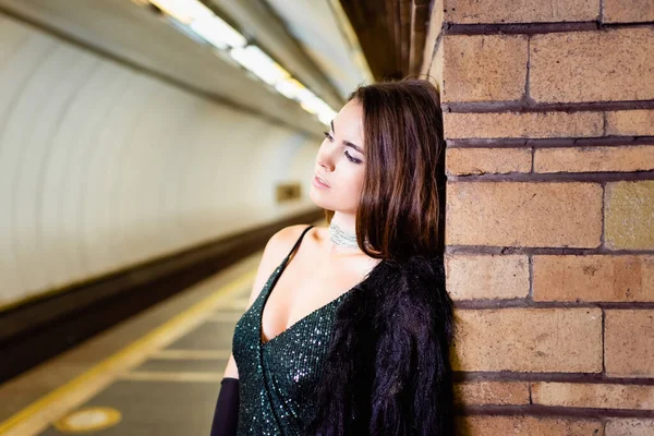 Sensual young woman leaning on brick column while standing on metro platform - foto de stock