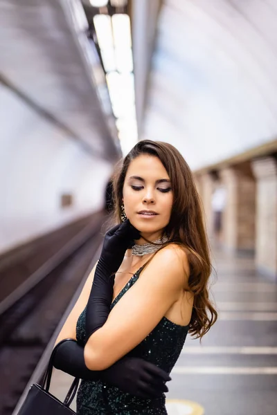 Verführerische Frau in elegantem schwarzen Kleid steht auf U-Bahnsteig — Stockfoto