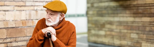 Homme âgé en pull et casquette assis avec bâton de marche à la station de métro, bannière — Photo de stock