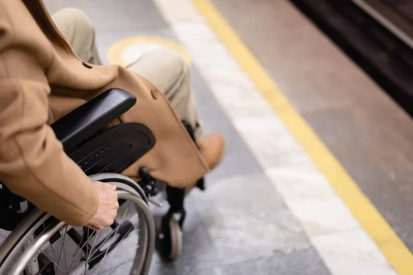 Cropped view of blurred handicapped man in wheelchair on subway platform - foto de stock