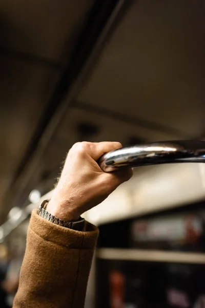 Cropped view of aged man holding handrail in wagon of underground train — Stock Photo