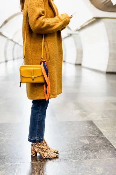 Teilbild einer stilvollen Frau in Herbstkleidung, die am U-Bahnhof per Smartphone Nachrichten sendet — Stockfoto