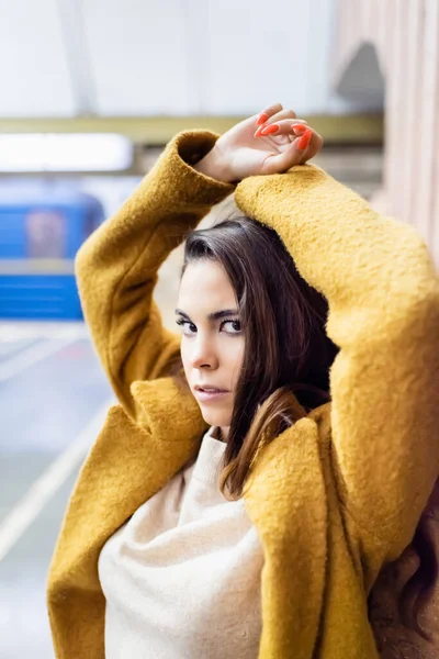 Jeune femme élégante en manteau d'automne regardant la caméra tout en posant à la station de métro — Photo de stock