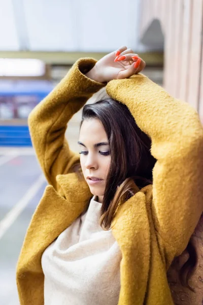Стильная женщина в осеннем пальто позирует на станции метро с поднятыми руками — стоковое фото