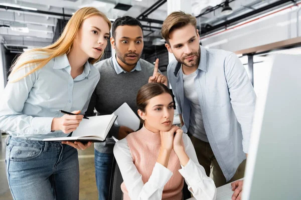 Indischer Geschäftsmann mit Idee in der Nähe von Kollegen und Computer im verschwommenen Vordergrund — Stockfoto