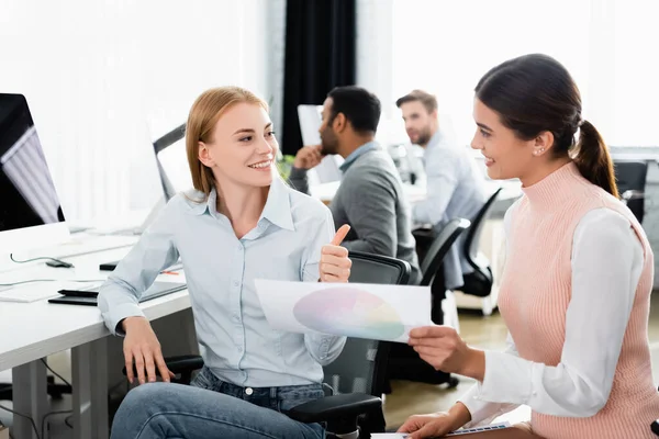 Donna d'affari sorridente che mostra come vicino collega con campioni colorati in ufficio — Foto stock