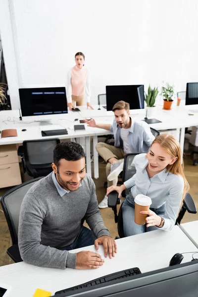 Empresários multiétnicos alegres que olham para o computador no escritório — Fotografia de Stock