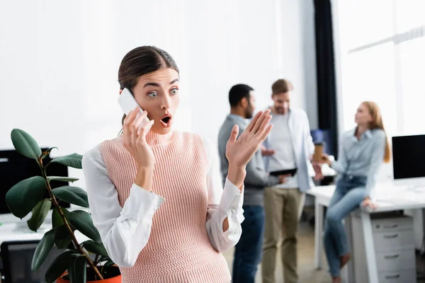 Scioccata donna d'affari che parla sullo smartphone mentre lavora in ufficio — Foto stock