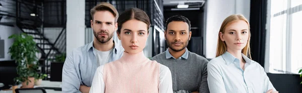 Jóvenes empresarios multiculturales mirando a la cámara en la oficina, pancarta - foto de stock