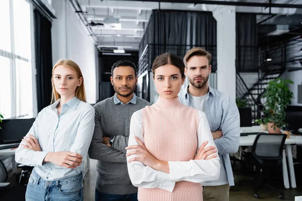 Empresarios multiculturales con brazos cruzados mirando a la cámara en la oficina - foto de stock