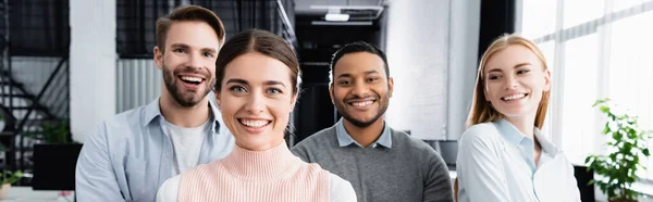 Multiethnic businesspeople smiling at camera in office, banner — Stock Photo