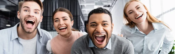 Positive multicultural businesspeople looking at camera in office, banner — Stock Photo