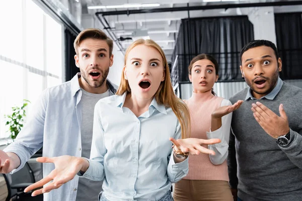 Empresários multiculturais chocados olhando para a câmera no escritório — Fotografia de Stock