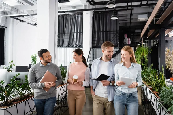 Souriant hommes d'affaires multiethniques avec café à ho et tablette numérique marche dans le bureau — Photo de stock