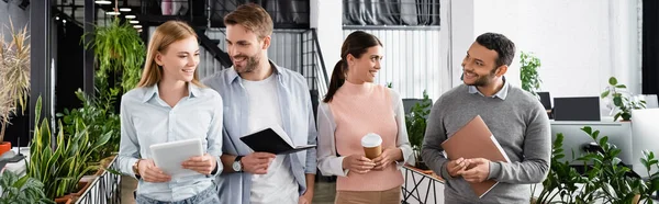 Positive multikulturelle Geschäftsleute mit digitalem Tablet, Coffee to go und Notizbuch im Büro, Banner — Stockfoto