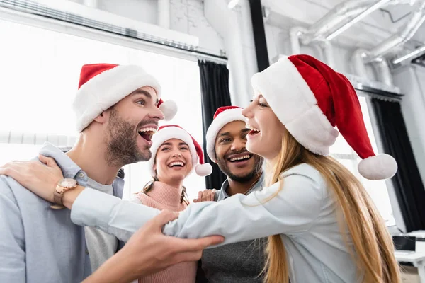 Улыбающиеся мультиэтнические предприниматели обнимаются во время празднования Рождества на посту — стоковое фото