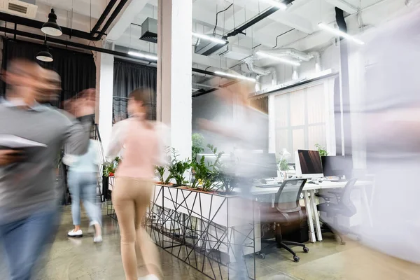 Motion blur of young businesspeople walking in modern office — Stock Photo