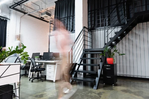 Desenfoque de movimiento de las mujeres de negocios caminando cerca de computadoras en la oficina - foto de stock