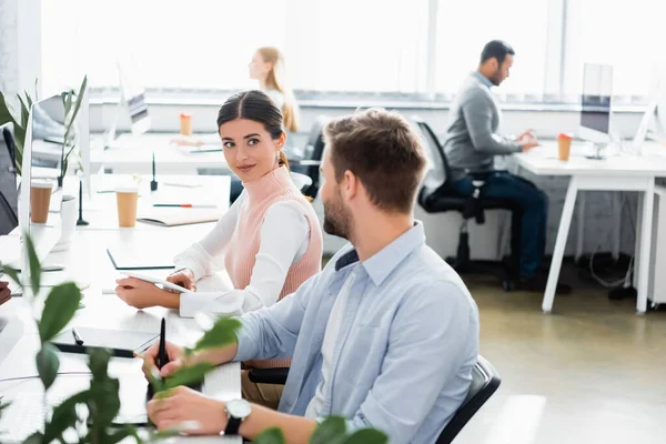 Businesswoman looking at colleague while using digital tablet in office — Stock Photo