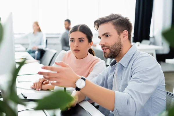 Geschäftsmann zeigt auf Computermonitor neben Amtskollegen — Stockfoto