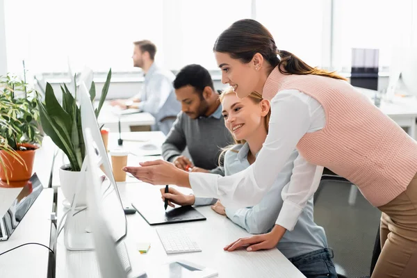 Mujeres de negocios sonrientes utilizando gráficos tableta y computadora en la oficina - foto de stock