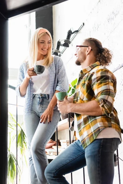 Молодой человек и женщина держат чашки кофе, разговаривая по лестнице в кафе — стоковое фото