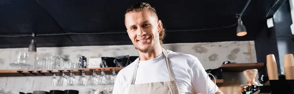 Jeune beau barista souriant à la caméra dans le café, bannière — Photo de stock