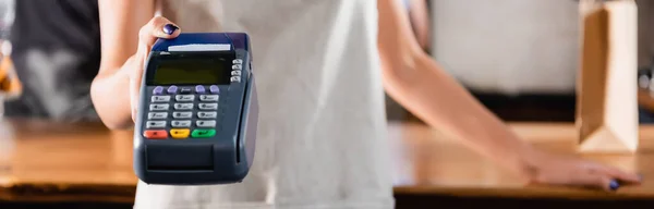 Partial view of barista holding payment terminal, blurred background, banner — Stock Photo