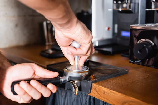 Cropped view of barista pressing ground coffee in portafilter — Stock Photo