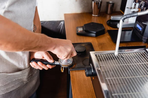 Vista parcial de barista pressionando café em portafilter perto da máquina de café — Fotografia de Stock