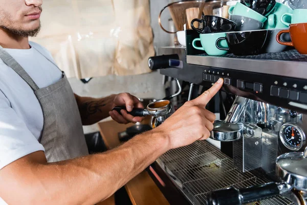 Cropped view of barista pushing button on coffee machine while holding portafilter — Stock Photo