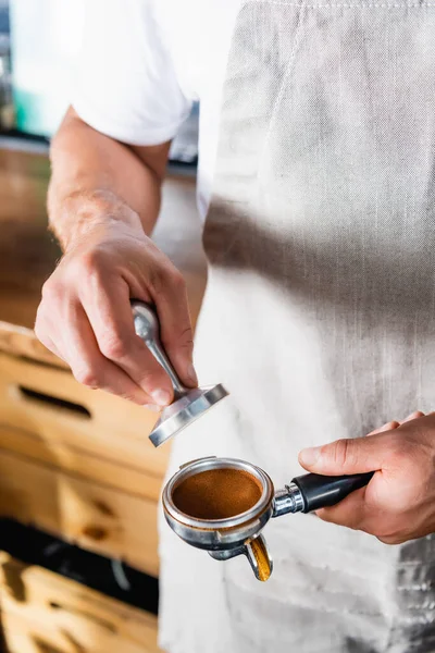 Vista cortada de barista prendendo imprensa e portafilter com café moído torrado — Fotografia de Stock